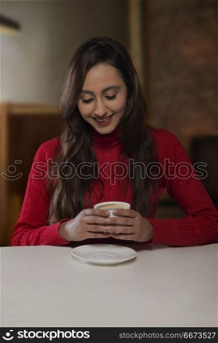 Smiling young woman having cup of coffee