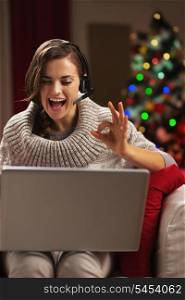 Smiling young woman having video chat with family in front of christmas tree