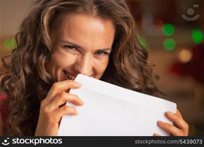 Smiling young woman hiding behind envelope