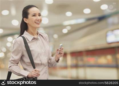 Smiling young woman holding mobile phone