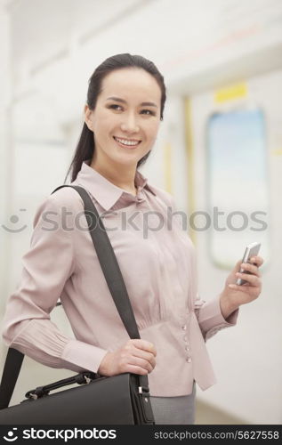 Smiling young woman holding mobile phone