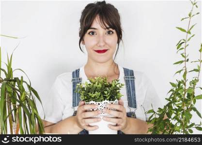 smiling young woman holding potted plant