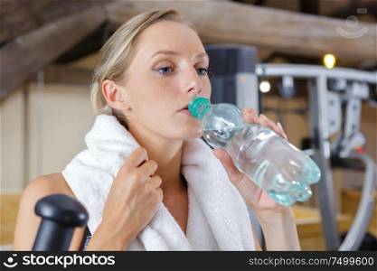smiling young woman holding water bottle in gym