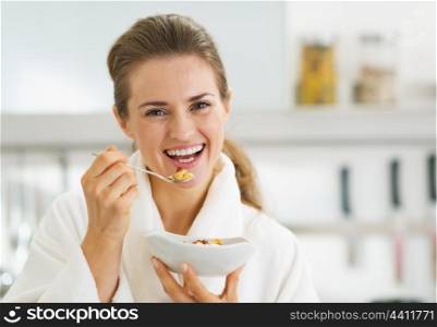 Smiling young woman in bathrobe having healthy breakfast