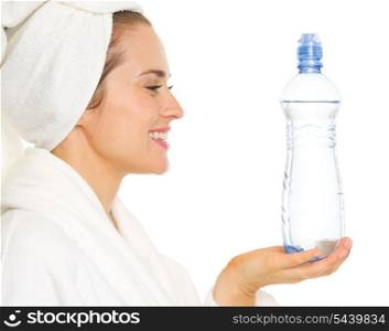 Smiling young woman in bathrobe holding water bottle