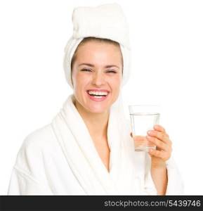 Smiling young woman in bathrobe with glass of water
