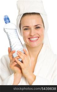 Smiling young woman in bathrobe with water bottle
