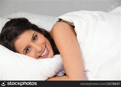 Smiling young woman in bed