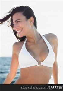 Smiling young woman in bikini against sea