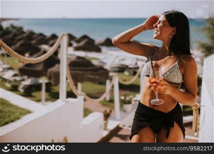 Smiling Young Woman in Bikini Enjoying Vacation on the Beach while drinking cocktail