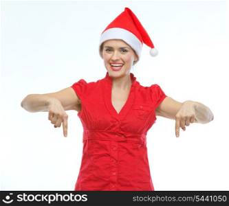 Smiling young woman in Christmas hat pointing down