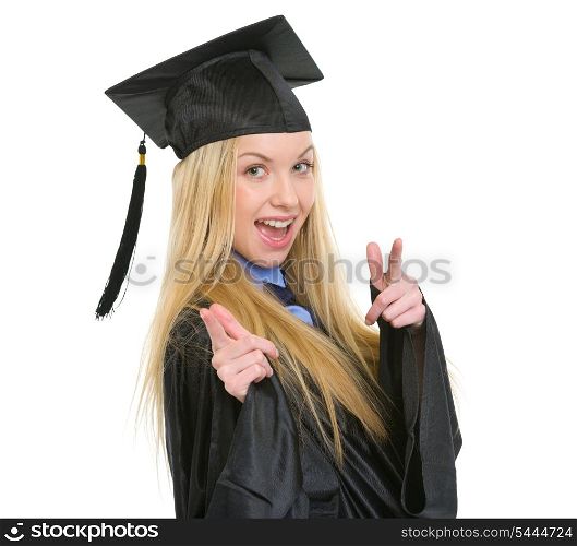 Smiling young woman in graduation gown pointing in camera