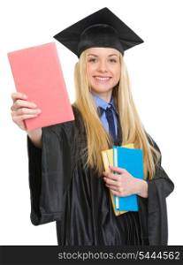Smiling young woman in graduation gown showing book