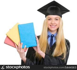 Smiling young woman in graduation gown showing books