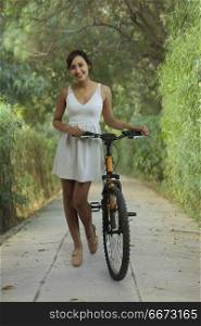 Smiling young woman in park with bicycle