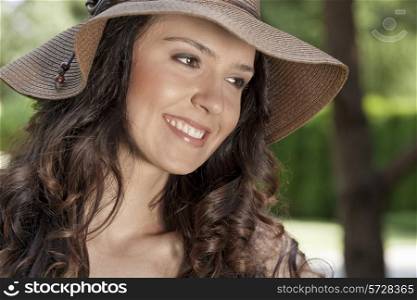 Smiling young woman in sunhat looking away in park