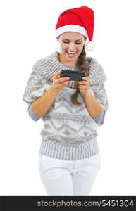 Smiling young woman in sweater and christmas hat reading sms