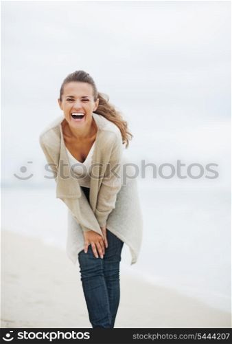 Smiling young woman in sweater having fun time on lonely beach