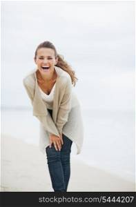 Smiling young woman in sweater having fun time on lonely beach