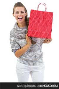 Smiling young woman in sweater showing christmas shopping bag