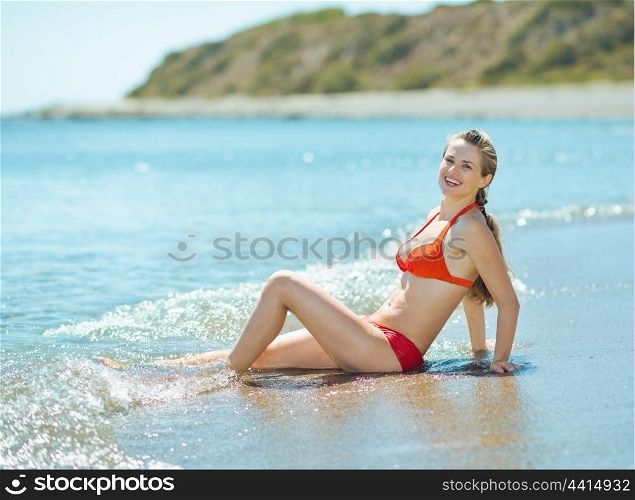 Smiling young woman in swim suite laying at seaside