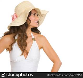 Smiling young woman in swimsuit and hat looking on copy space