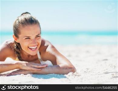 Smiling young woman in swimsuit enjoying laying on beach