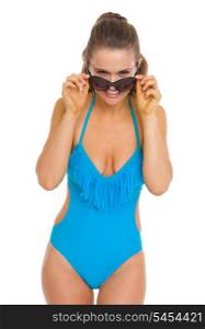 Smiling young woman in swimsuit looking out from sunglasses