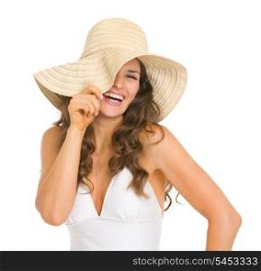 Smiling young woman in swimsuit playing with hat