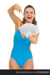 Smiling young woman in swimsuit pointing on fan of dollars