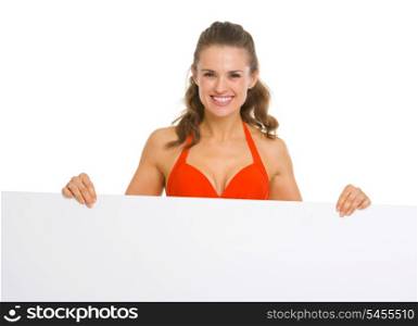 Smiling young woman in swimsuit showing blank billboard
