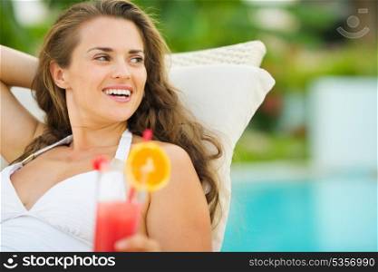 Smiling young woman in swimsuit with cocktail looking on copy space