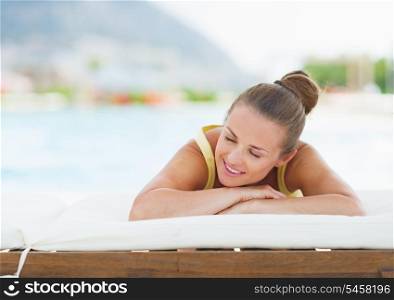 Smiling young woman laying on chaise-longue