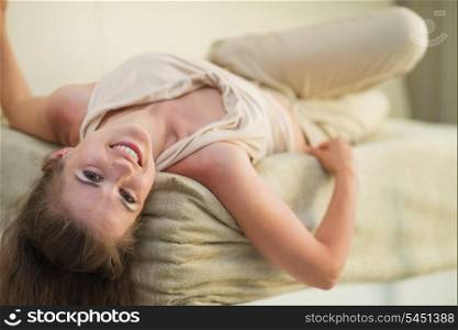 Smiling young woman laying on divan
