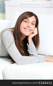 Smiling young woman laying on sofa