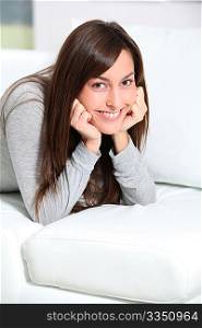 Smiling young woman laying on sofa