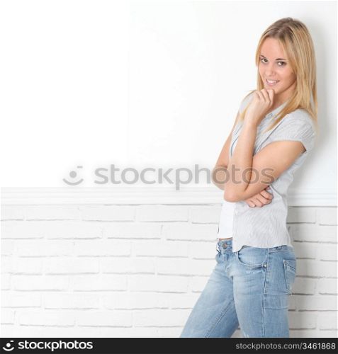 Smiling young woman leaning on white wall
