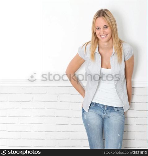 Smiling young woman leaning on white wall