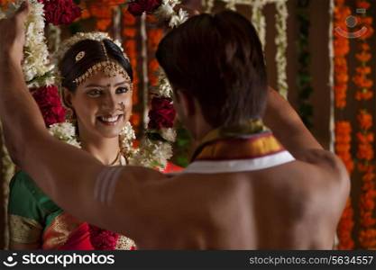 Smiling young woman looking at husband during wedding ceremony