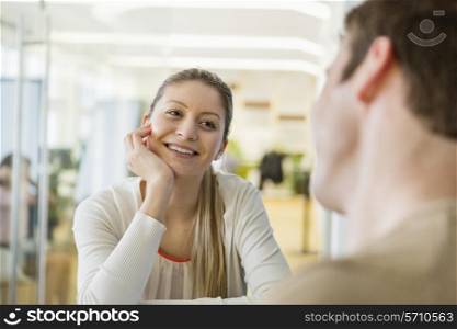 Smiling young woman looking at man in restaurant