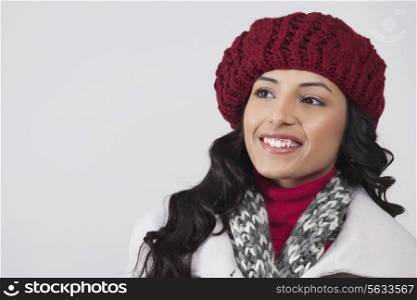 Smiling young woman looking away over grey background