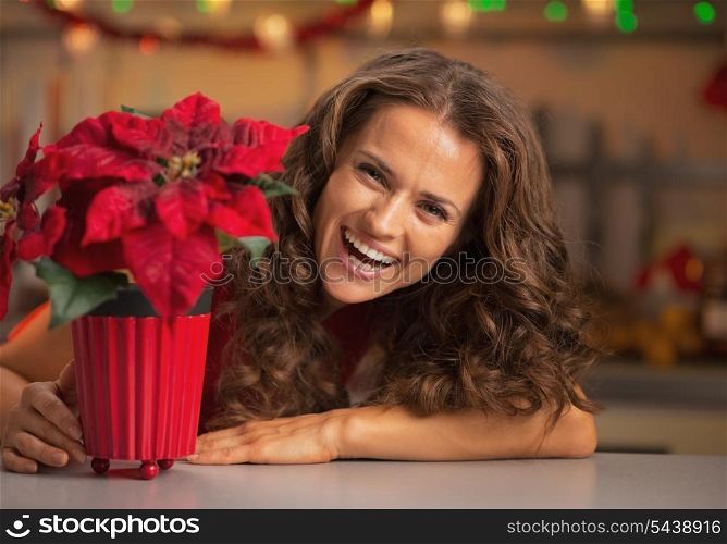 Smiling young woman looking out from christmas rose in christmas decorated kitchen