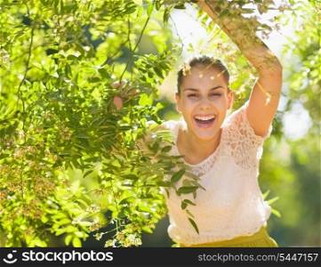 Smiling young woman looking out from foliage