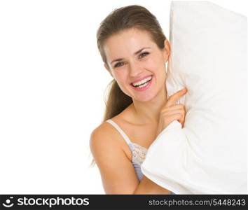 Smiling young woman looking out from pillow