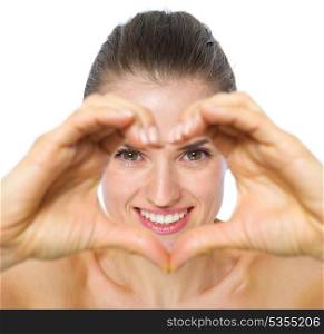 Smiling young woman looking through heart shaped hands