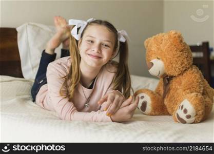 smiling young woman lying bed with teddy bear