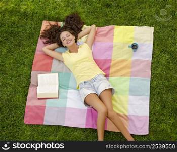 Smiling young woman lying on her back on a blanket and relaxing