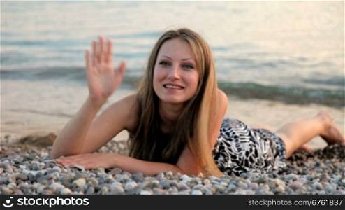 smiling young woman lying on the beach at sunset