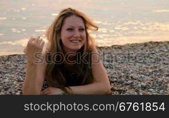 smiling young woman lying on the beach at sunset