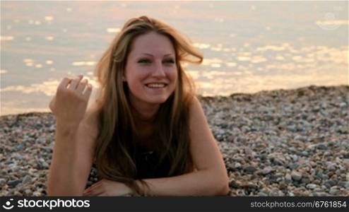 smiling young woman lying on the beach at sunset